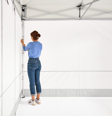 The woman assembles the 2 closed side walls on the folding gazebo.