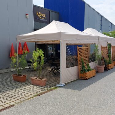 2 folding gazebo measuring 4.5x3 m stand in front of the Käser bakery in Vilshofen. They serve as canopies for the guests.